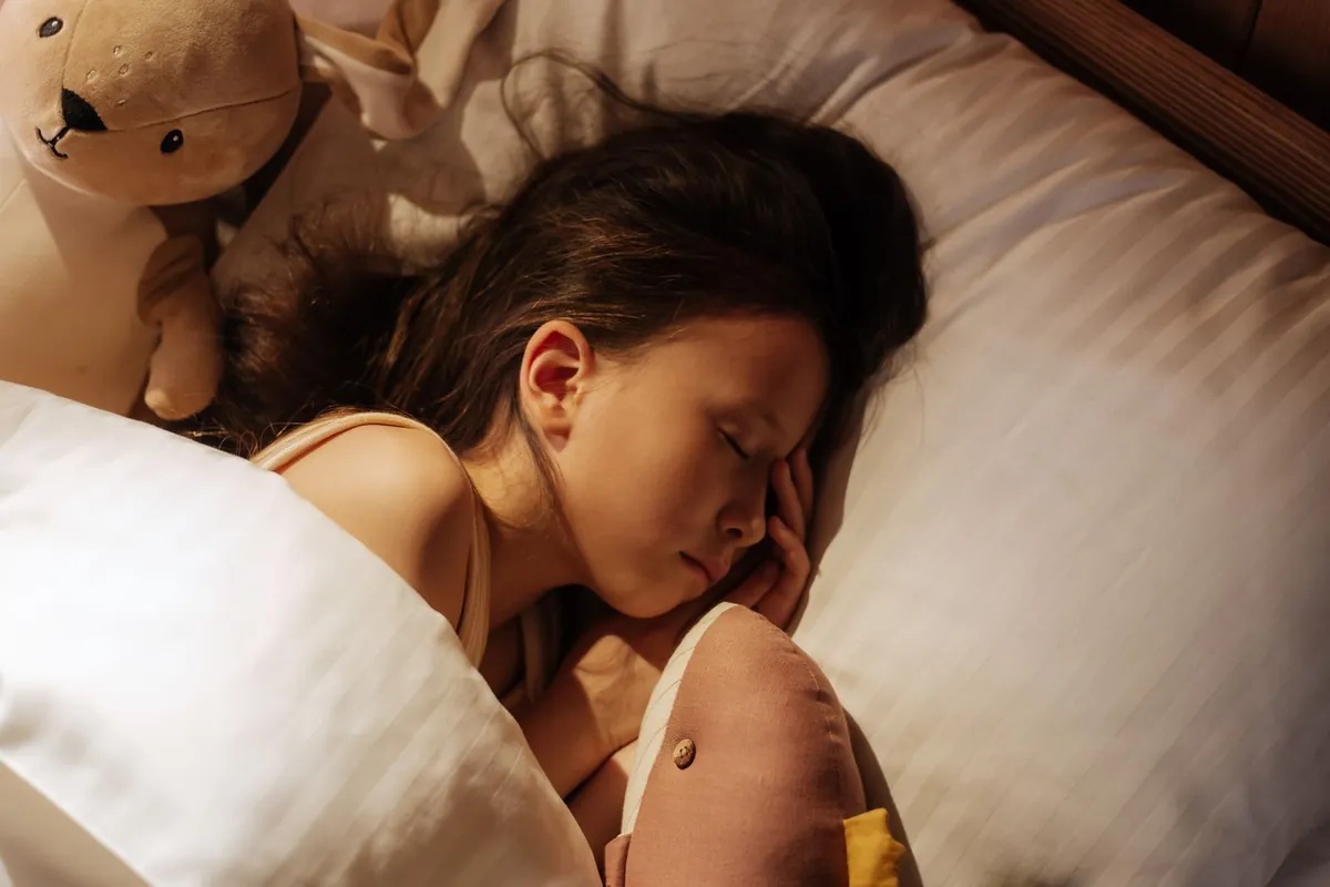 What is considered good sleep for kids: young girl asleep hugging a teddy bear