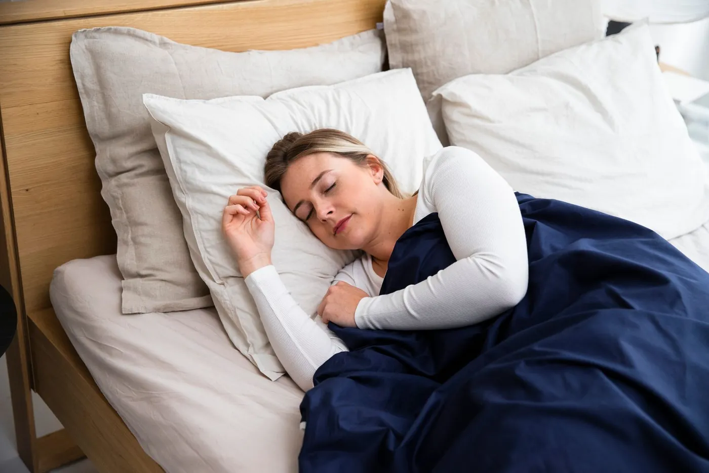 What is considered good sleep: woman sleeping soundly under a navy duvet